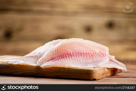 Fresh fish fillet on a cutting board. On a wooden background. High quality photo. Fresh fish fillet on a cutting board.