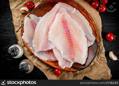 Fresh fish fillet on a wooden plate. On a black background. High quality photo. Fresh fish fillet on a wooden plate.