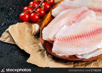 Fresh fish fillet on a wooden plate. On a black background. High quality photo. Fresh fish fillet on a wooden plate.