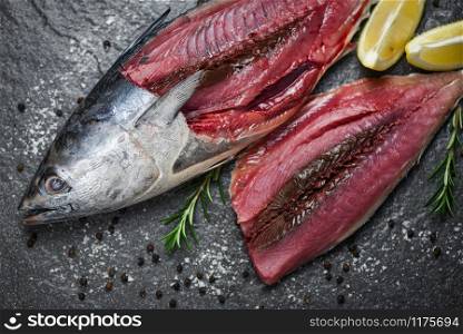 Fresh fish fillet sliced for steak or salad with herbs spices rosemary and lemon / Raw fish seafood on black plate background , Longtail tuna , Eastern little tuna fillet ingredients for cooking food