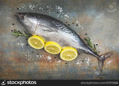 Fresh fish with herbs spices rosemary and lemon / Raw fish seafood on black plate background top view , Longtail tuna , Eastern little tuna fish