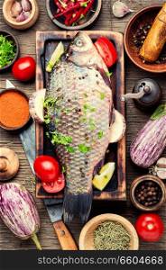 Fresh fish with ingredients for cooking on cutting board.Cooking concept.Healthy diet. Fresh raw fish and food ingredients