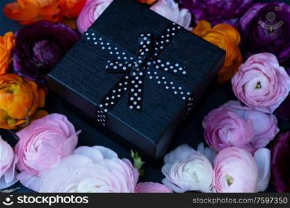 Fresh flowers with gift box, close up on black background. Festive party concept