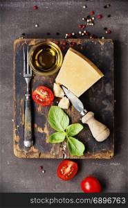 Fresh food ingredients for italian cuisine (Parmigiano, tomato, basil, olive oil) on rustic background. Top view