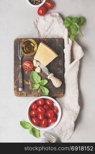 Fresh food ingredients for italian cuisine (Parmigiano, tomato, basil, olive oil) on rustic background. Top view