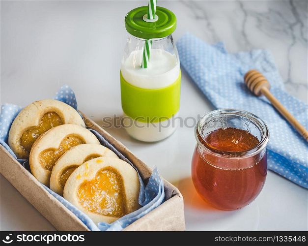 Fresh, fragrant handmade cookies, glass of milk and jar of honey. Close-up, top view. Tasty and healthy eating concept. Fresh cookies, glass of milk and jar