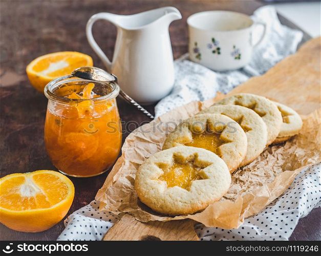 Fresh, fragrant handmade cookies, lying on a cutting board and jam of orange slices. Close-up, side view. Tasty and healthy eating concept. Fresh cookies and orange jam. Close-up, side view