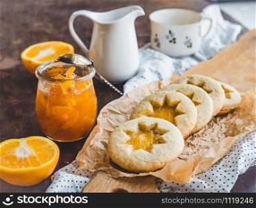 Fresh, fragrant handmade cookies, lying on a cutting board and jam of orange slices. Close-up, side view. Tasty and healthy eating concept. Fresh cookies and orange jam. Close-up, side view