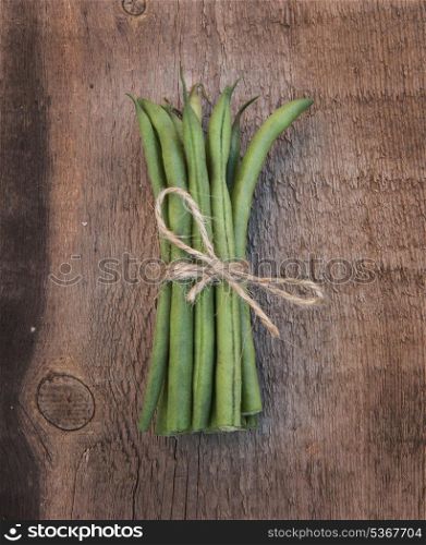 Fresh French beans tied with string on wooden background