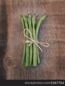 Fresh French beans tied with string on wooden background