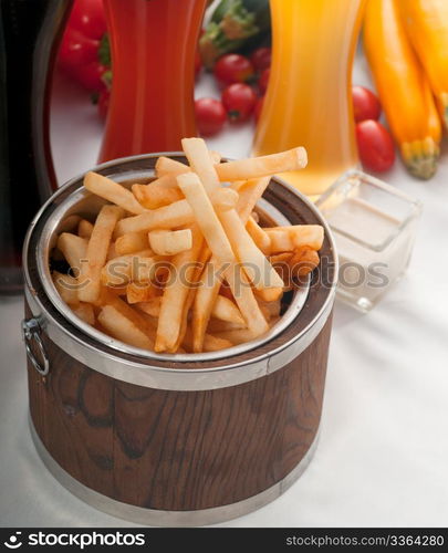 fresh french fries on a wood bucket with selection of beers and fresh vegetables on background