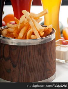 fresh french fries on a wood bucket with selection of beers and fresh vegetables on background