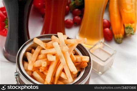 fresh french fries on a wood bucket with selection of beers and fresh vegetables on background