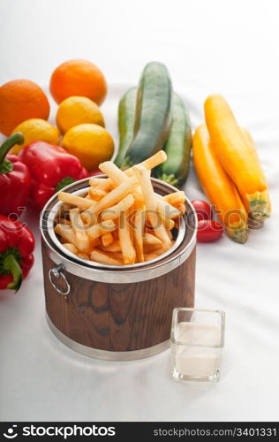 fresh french fries on a wood bucket with white dip sauce and fresh vegetables on background