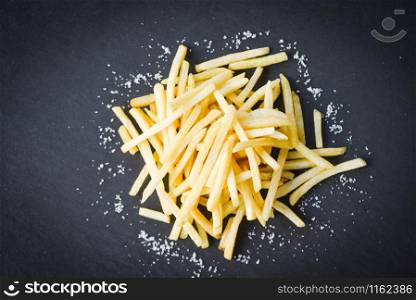 Fresh french fries with salt on black plate , top view copy space / Tasty potato fries for food or snack delicious Italian menu homemade
