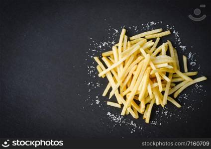 Fresh french fries with salt on black plate , top view copy space / Tasty potato fries for food or snack delicious Italian meny homemade ingredients
