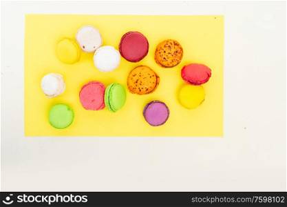 Fresh fresh macaroon sweets over yellow background, top view. Fresh macaroon confection