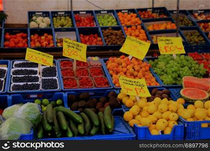Fresh fruit on a market stalll (text on tags: names and prices of various fruits in Dutch, raspberries, apricots, grapes from Italy and fresh harvested lemons )