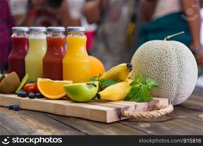 Fresh fruits and juice bottle on table. Food and drink concept. Healthy food and vitamins c theme. Crowd people in background