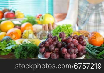 Fresh fruits and vegetables in the kitchen. In the background, a pregnant woman