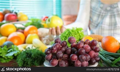 Fresh fruits and vegetables in the kitchen. In the background, a pregnant woman