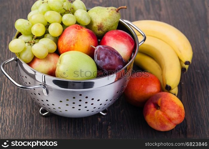 Fresh fruits in colander. Fresh fruits in colander on wooden table.