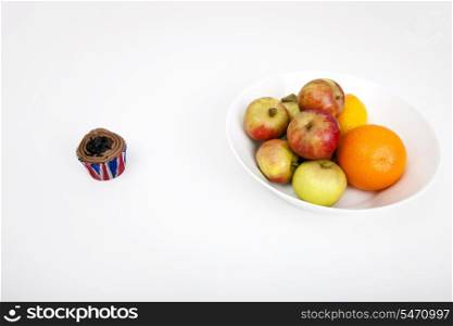 Fresh fruits in plate with cupcake against white background