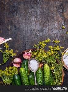 Fresh garden cucumber with ingredients for preserving: spoon of salt,dill and garlic on rustic wooden background, top view,place for text