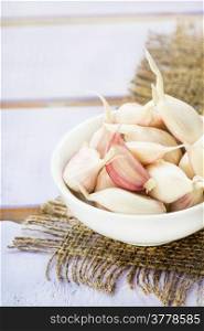 Fresh garlic in bowl over rustic background, selective focus