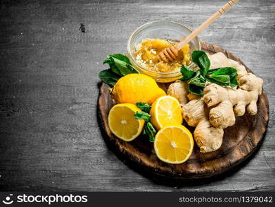 Fresh ginger with honey and lemons on the Board. On the black chalkboard.. Fresh ginger with honey and lemons on the Board.