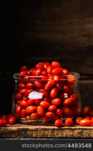 Fresh Goji berries in glass jar on dark wooden background, close up