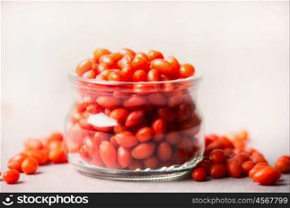 Fresh Goji berries in glass jar on light background, close up