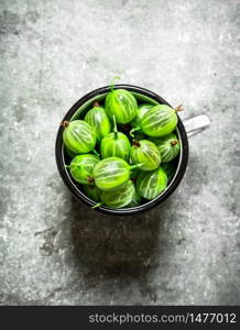 Fresh gooseberries in a Cup. On a stone background.. Fresh gooseberries in a Cup. On stone background.