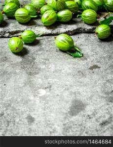 Fresh gooseberries with leaves. On the stone table.. Fresh gooseberries with leaves. On stone table.