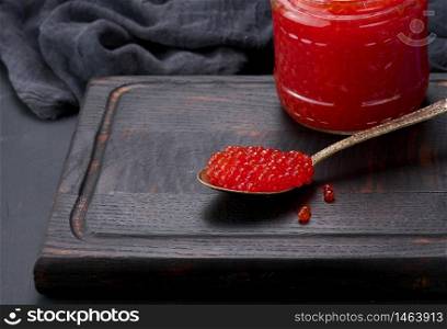 fresh grainy red caviar in a glass jar on a wooden table