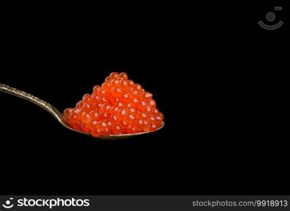 fresh grainy red chum salmon caviar in a metal spoon, delicious and healthy food, copy space