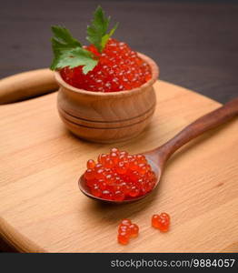 fresh grainy red chum salmon caviar in a wooden spoon, delicious and healthy food, close up