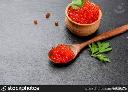 fresh grainy red chum salmon caviar in a wooden spoon, delicious and healthy food, close up