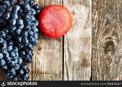 Fresh grapes and cheese on old wooden background