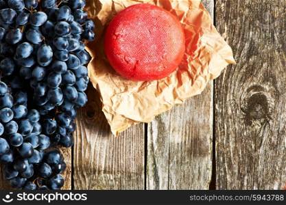 Fresh grapes and cheese on old wooden background