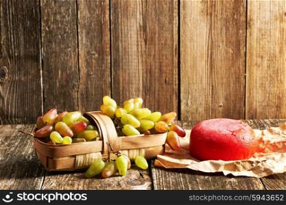 Fresh grapes and cheese on old wooden table