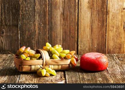 Fresh grapes and cheese on old wooden table