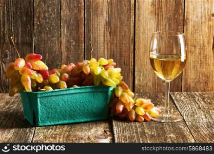 Fresh grapes and white wine on old wooden table