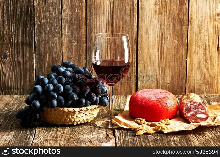 Fresh grapes, cheese and red wine on old wooden table