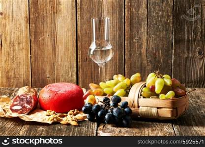 Fresh grapes, grappa and cheese on old wooden table
