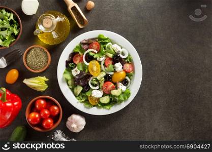 fresh greek salad in plate and ingredients on stone table