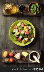 fresh greek salad in plate and ingredients on wooden table