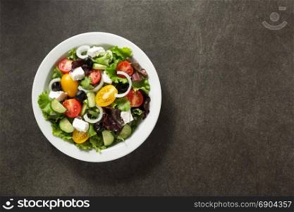 fresh greek salad in plate on stone table