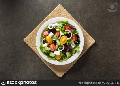 fresh greek salad in plate on stone table