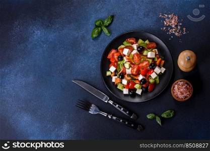Fresh greek salad with tomato, cucumber, bel pepper , olives and feta cheese on black plate. Greek salad with fresh vegetables, feta cheese and black olives